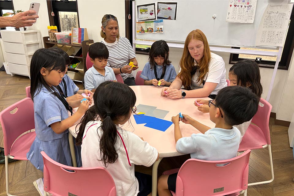 米国デンバーから来日した高校生と、日本の伝統文化である折り紙を通して英語で交流する児童たち