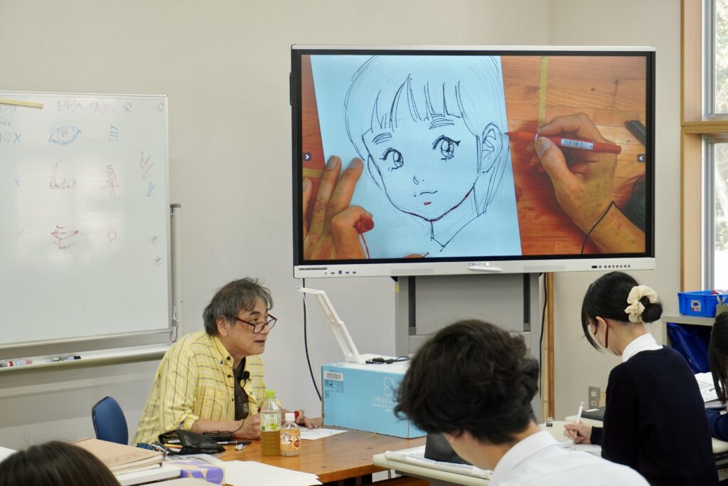 マンガ学科の授業の様子。マンガ家の富沢順先生が講師を務め、ペンを持つ手元を画面に映している