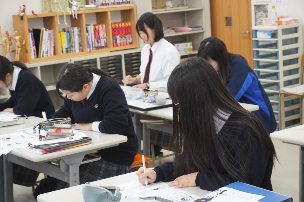 真剣にマンガを学ぶ生徒たち。机には多数のペンが入った筆箱などが見える