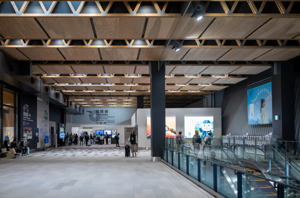 阿蘇くまもと空港の内観。床は白基調で、壁と柱は黒基調の中、天井の小国杉の木目が目を引き、温かみを感じさせる